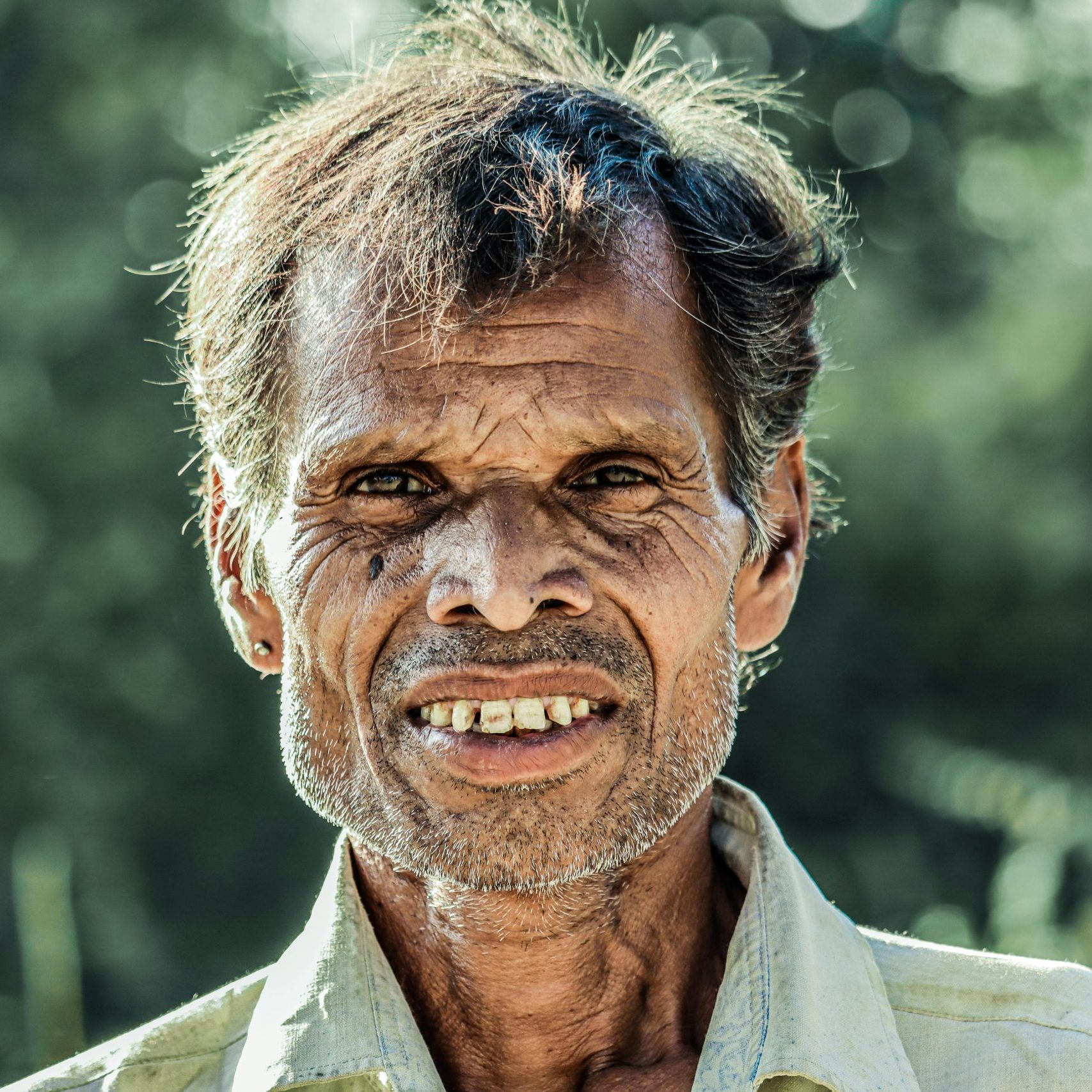 Close-up of a senior man smiling outdoors, capturing a moment of warmth and character.
